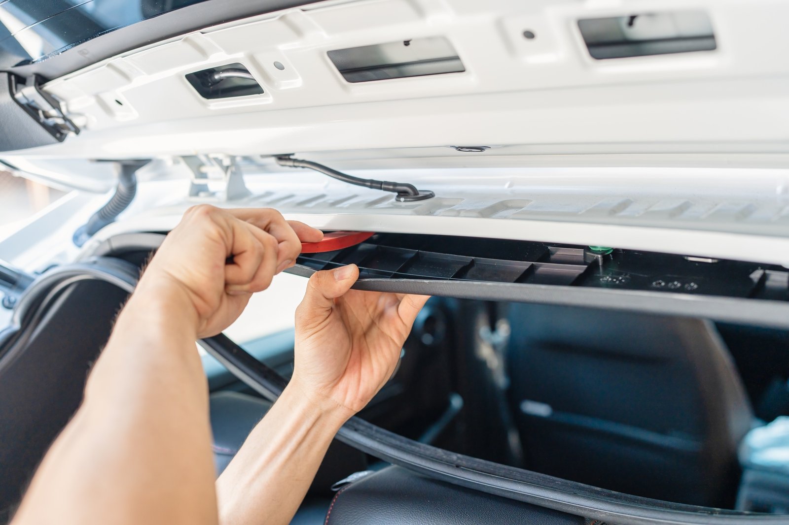Hand of mechanic using wedge removing and installing a dash cam inside a car at workshop